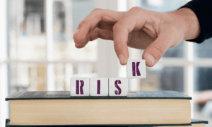 A hand stacking bricks that spell out risk.