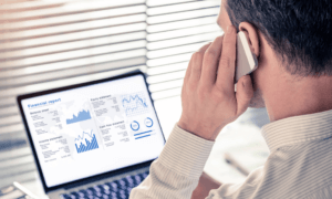 Someone looking at a computer and talking on the phone