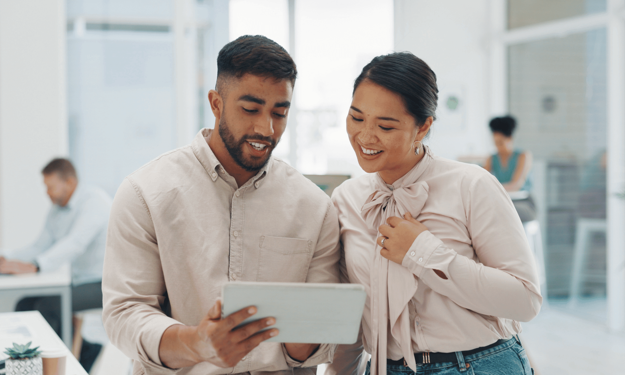 Two people looking at a tablet and smiling.
