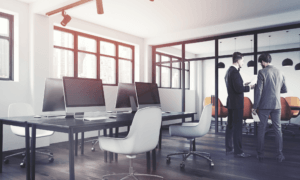 Two people in an office and holding papers.