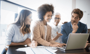 four people looking at a laptop.