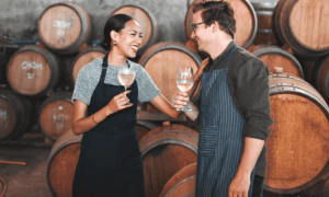 Two people smiling and holding wine.