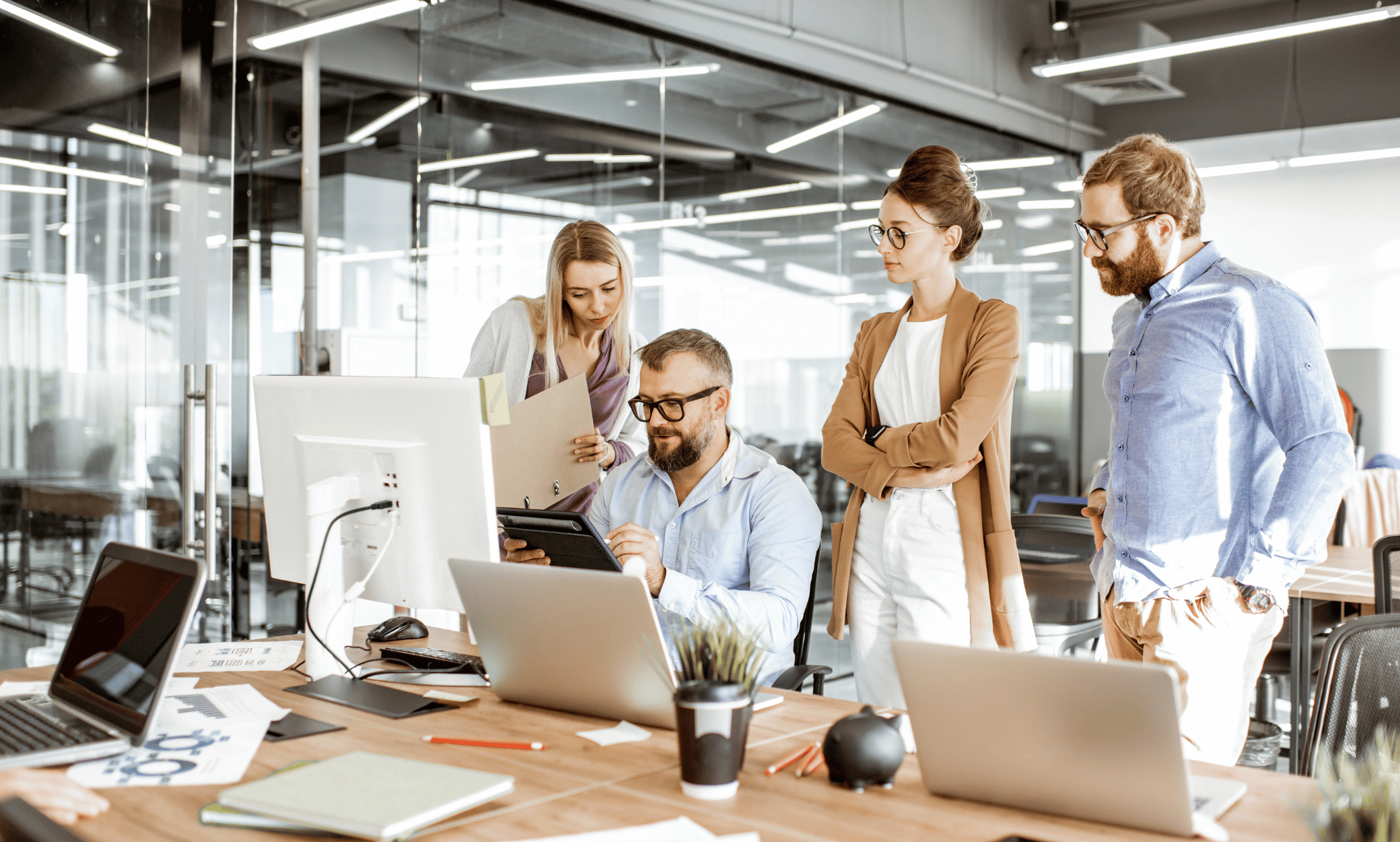 Four people looking at a tablet inside a office.