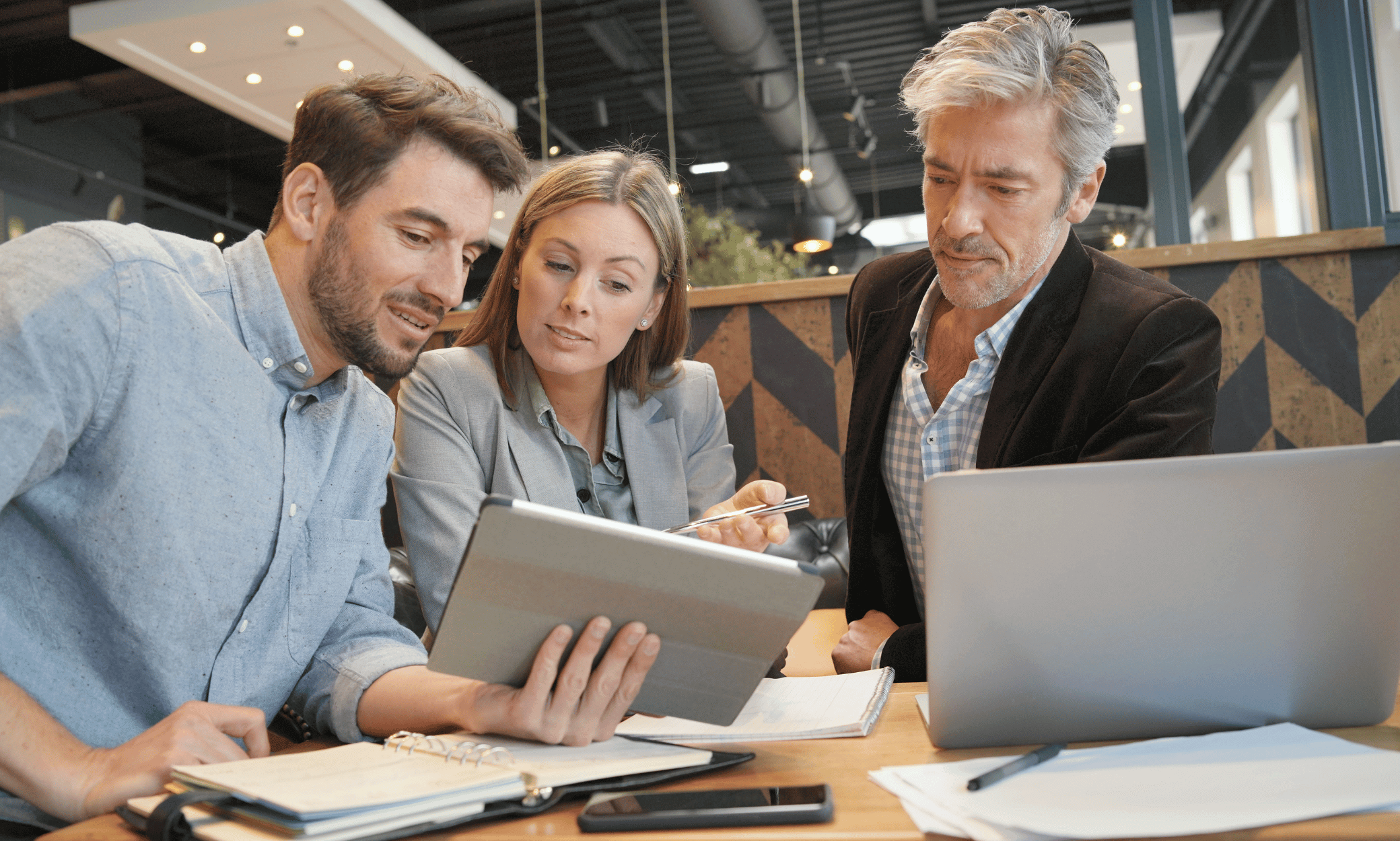 Three people looking at a tablet.