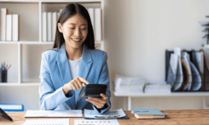 a person sitting at a desk using a calculator and a computer