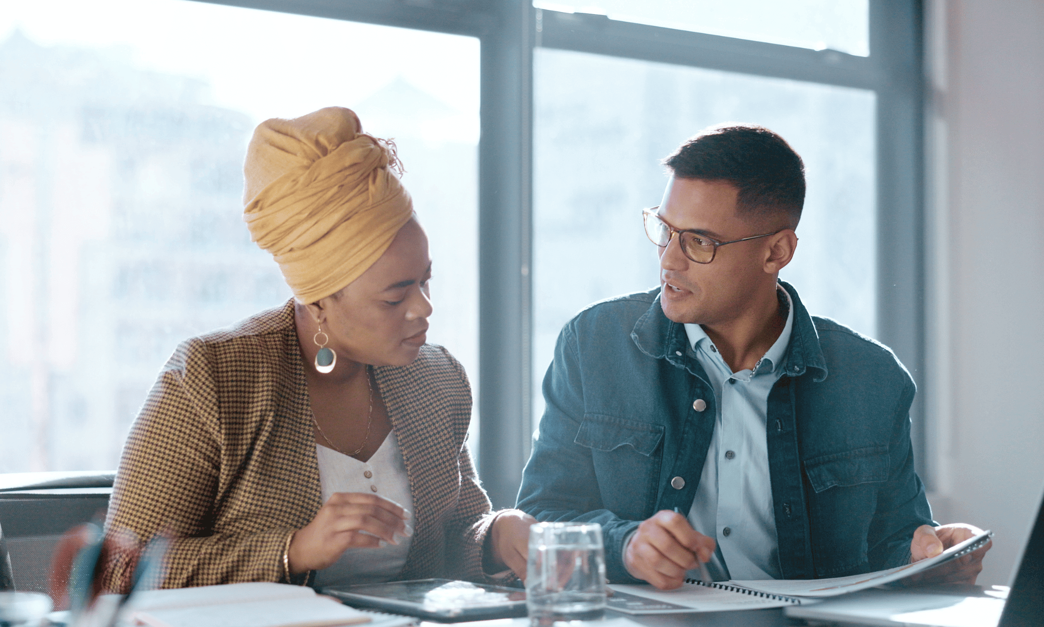 Two people sitting and looking at papers.