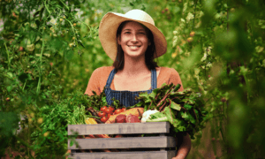 A person holding a box of veggies.