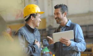 Two people smiling and one of them are holding a tablet.