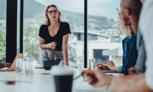 Someone standing at the head of the table an talking to a group.