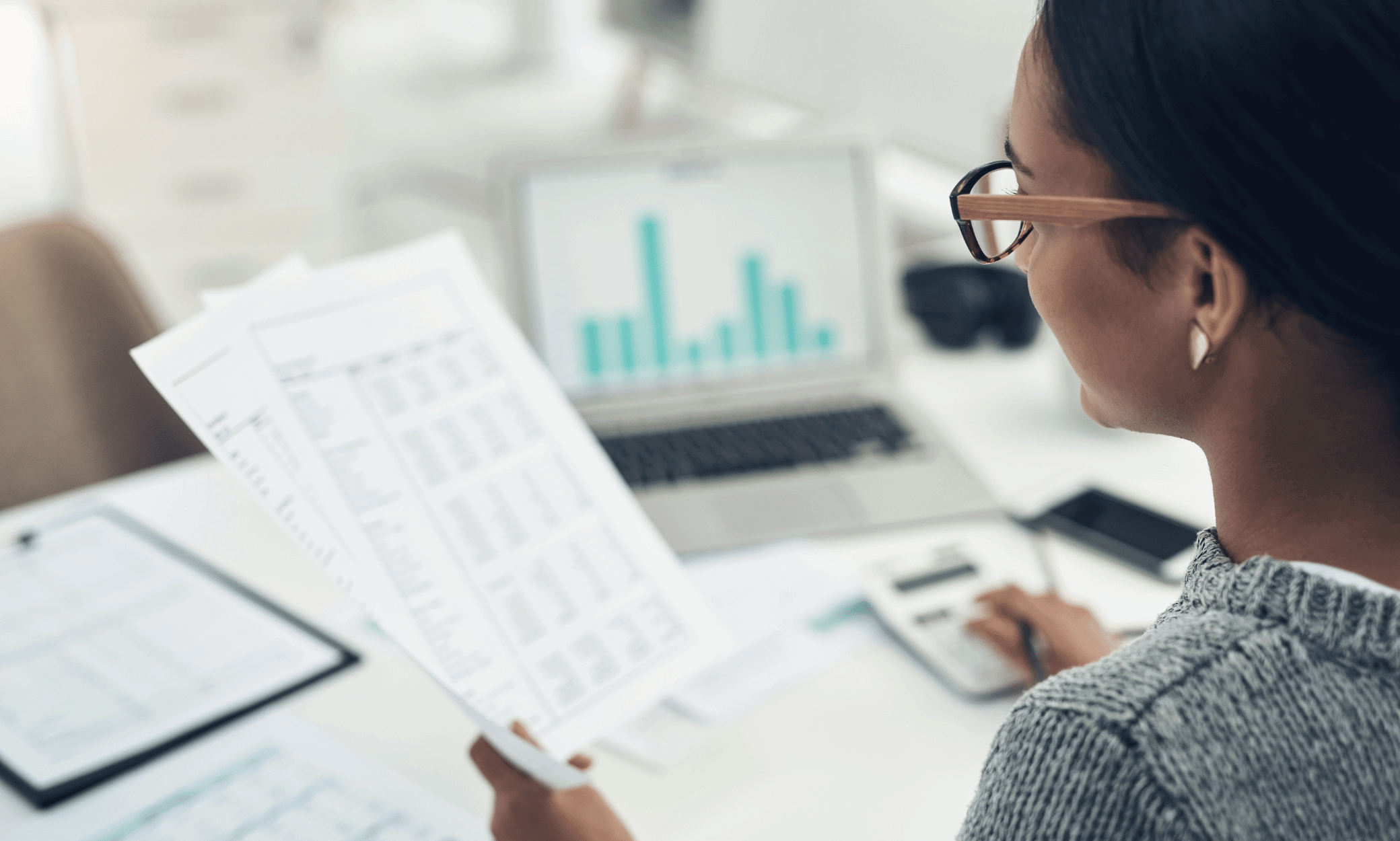 Someone looking at pieces of paper and a computer with financials.