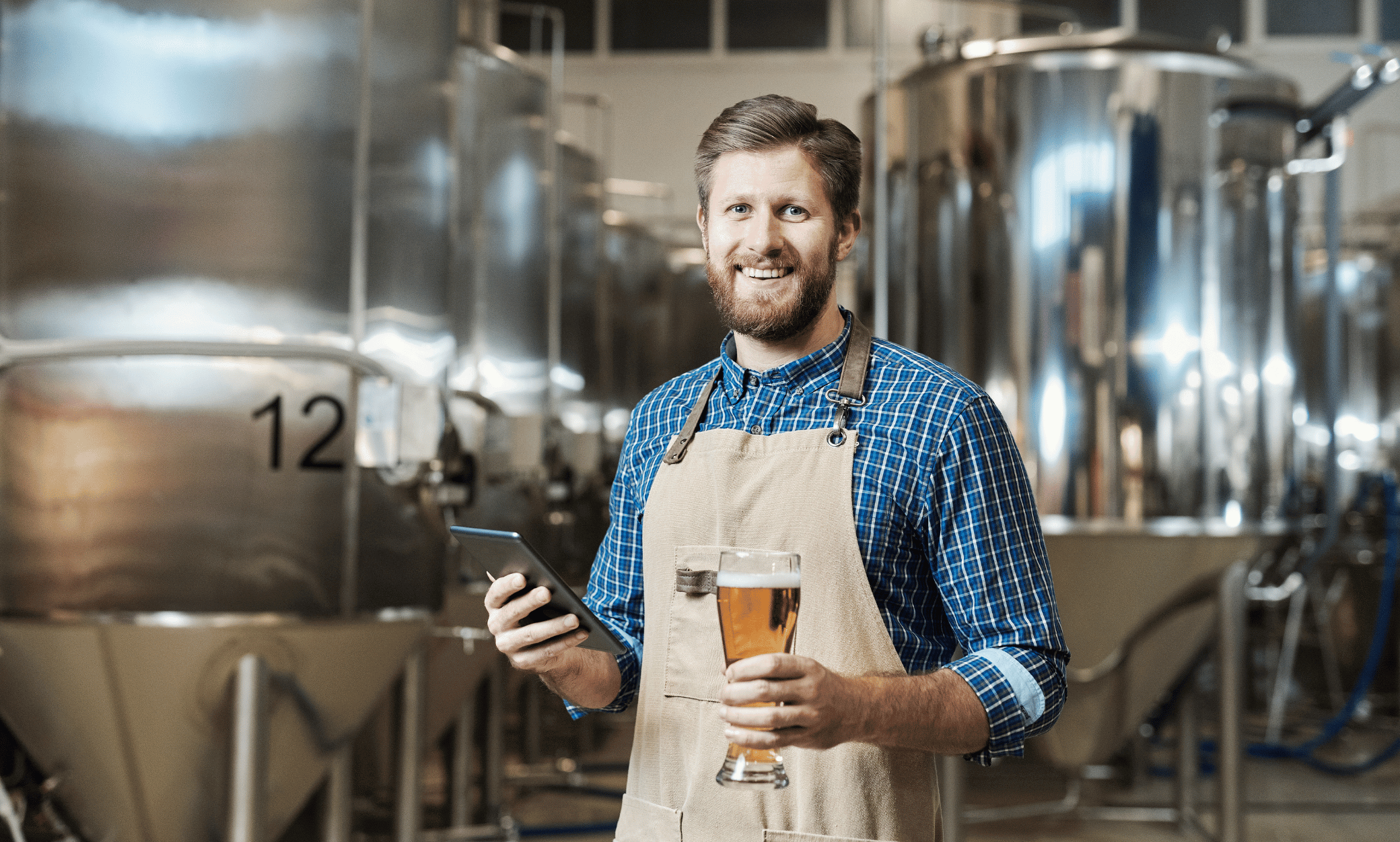 A person holding a beer and tablet.