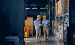 Two people walking in a warehouse and smiling.