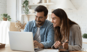 Two people looking at a computer and smiling