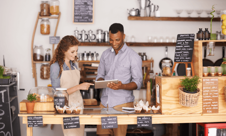 Two workers reading a tablet in a cafe.