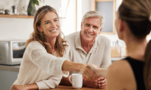 A couple shaking hands with another person.