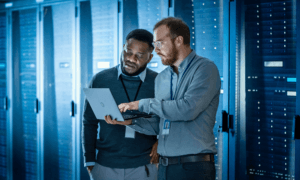 Two people looking at a laptop while one points at the screen.