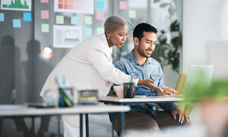 Two people looking at a computer and collaborating.