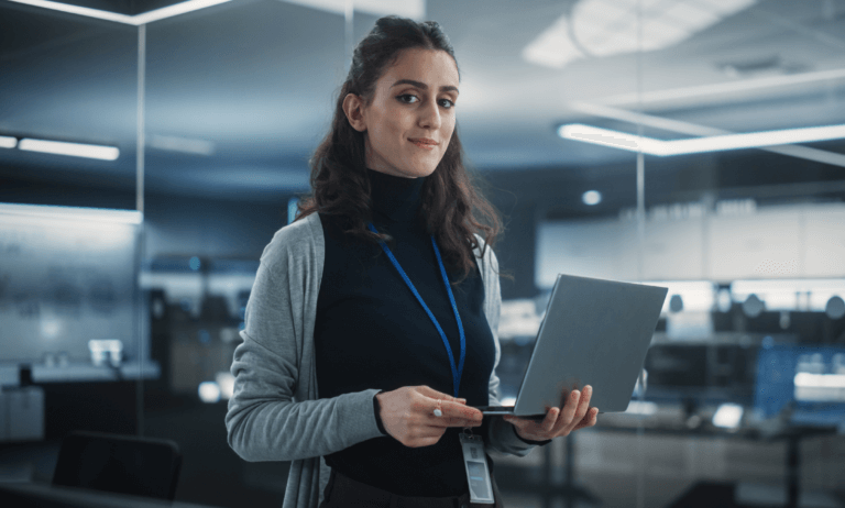 Person holding a laptop and slightly smiling at the camera.