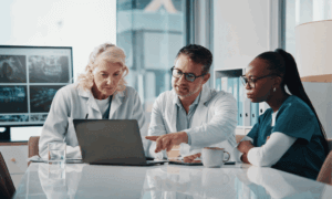 Three people looking at a laptop.