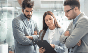 Three people looking at a clipboard