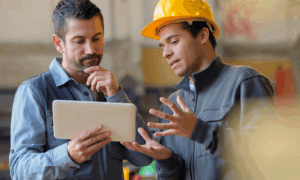 Two people reviewing work on a tablet in a construction setting.