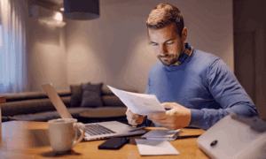 Person looking at papers in front of a laptop.