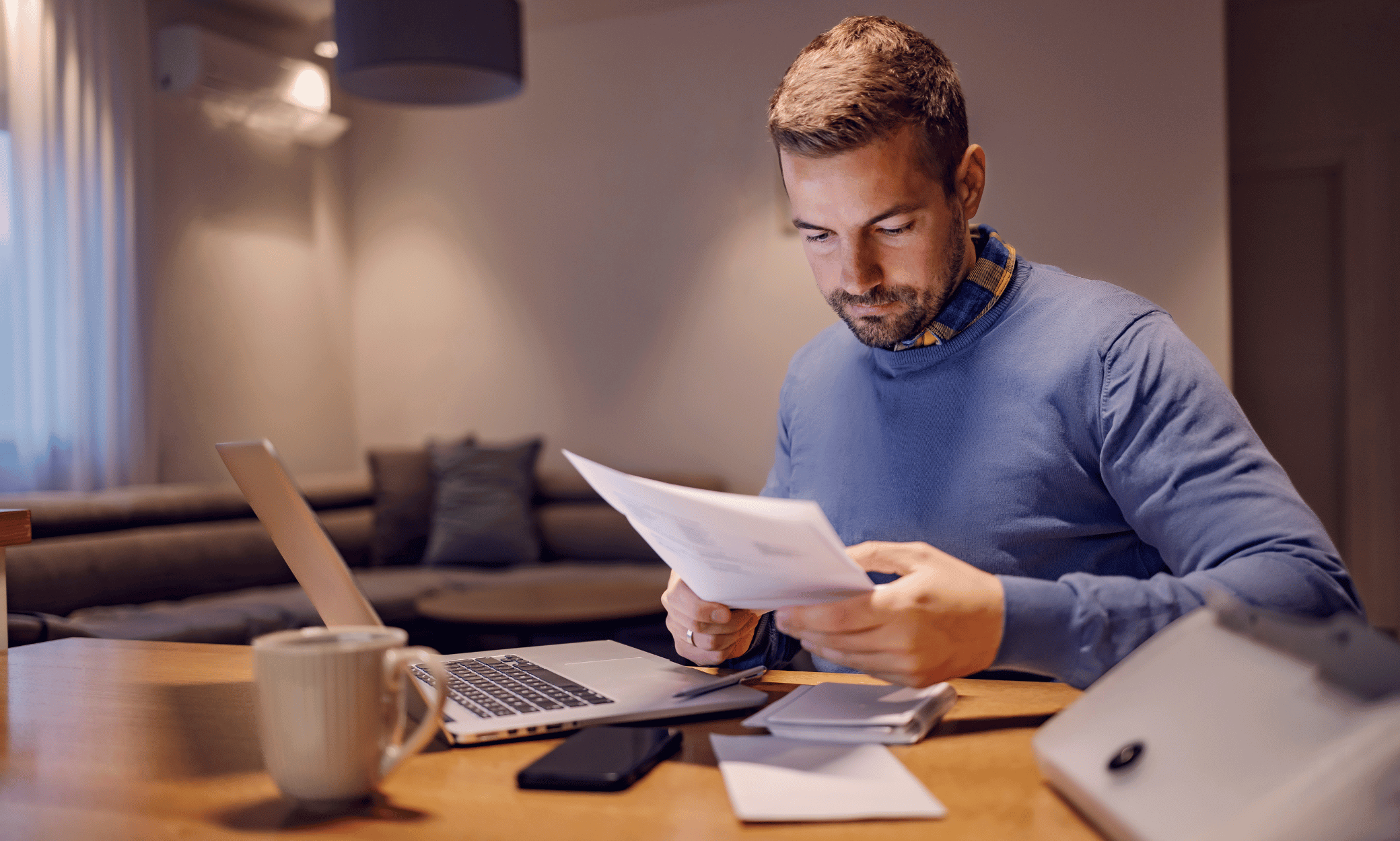 Person looking at papers in front of a laptop.