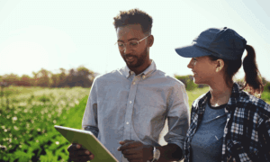 Two people looking at a tablet on a farm.