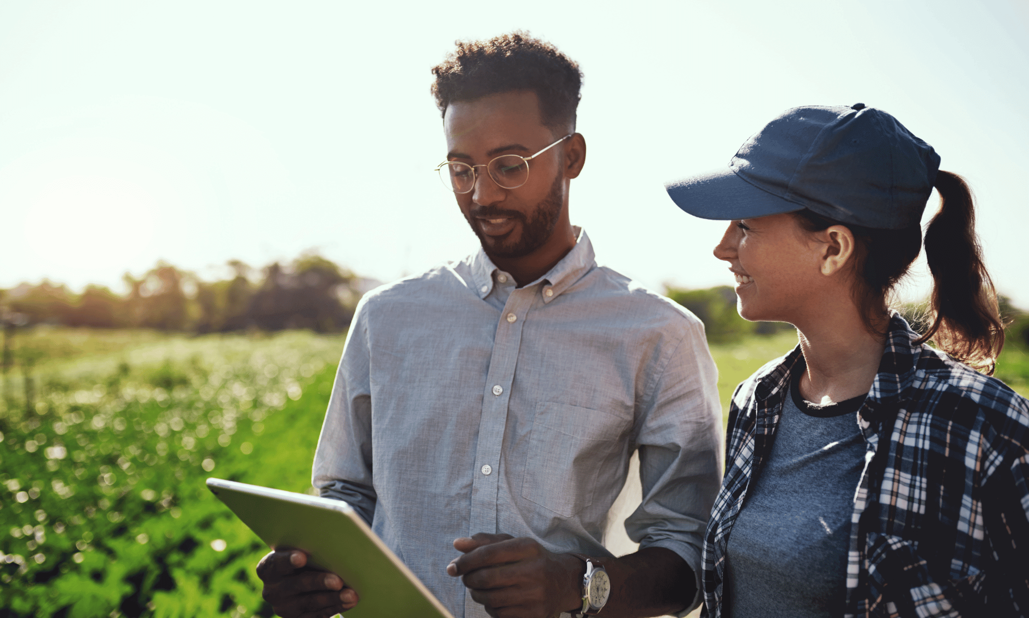 Two people looking at a tablet on a farm.