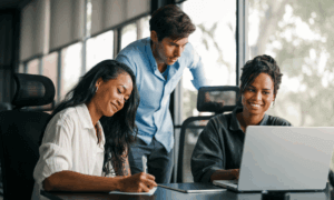Three people looking at a laptop.