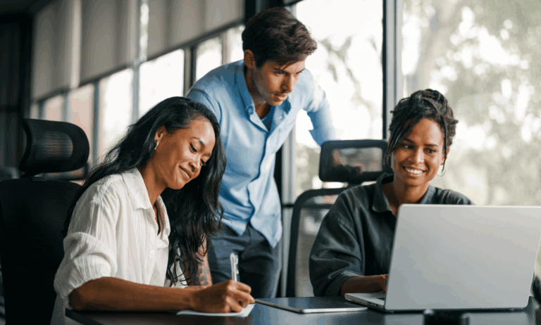 Three people looking at a laptop.