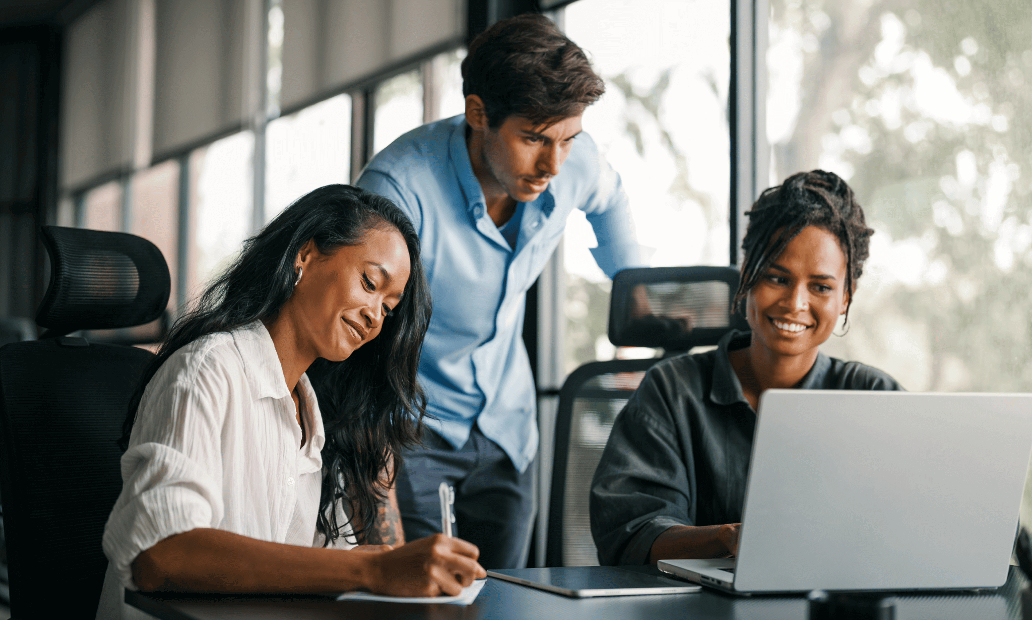 Three people looking at a laptop.