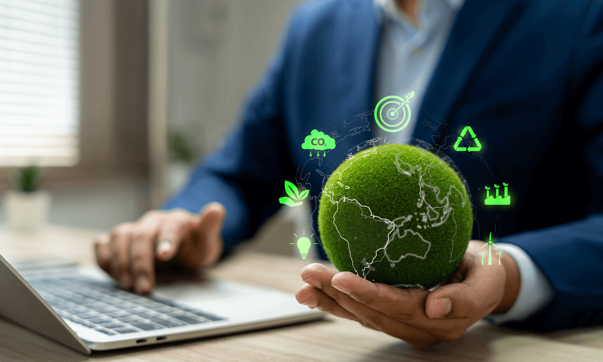 Someone using a laptop and holding a globe