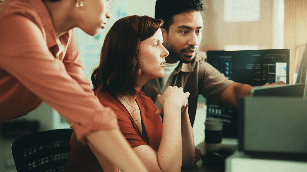 Three people looking at a computer.